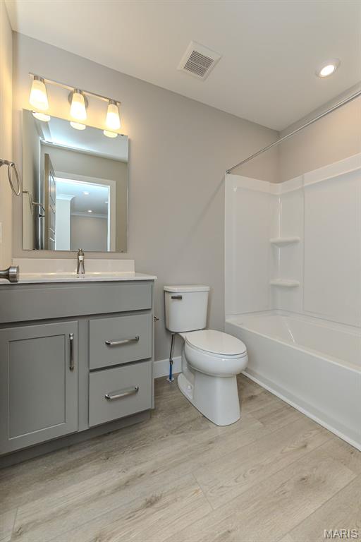 8919 E Gateway Hts Unit 94-804, Richmond Heights, MO 63144 - bathroom with toilet, vanity, wood finished floors, bathing tub / shower combination, and baseboards