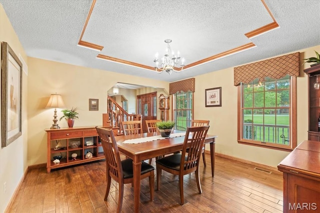 22 Fox Valley Ct, Lake St Louis, MO 63367 - dining room featuring a textured ceiling, a chandelier, wood-type flooring, a raised ceiling, and baseboards