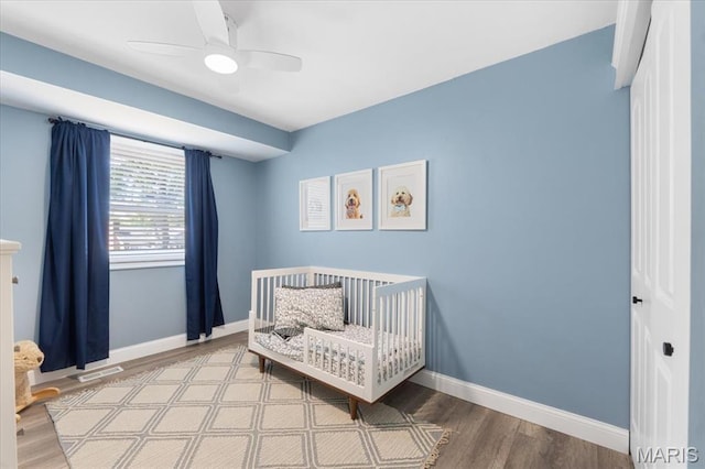 2774 Ashrock Dr, Saint Louis, MO 63129 - bedroom with wood finished floors, baseboards, ceiling fan, and a nursery area