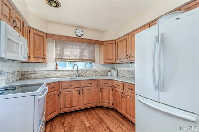 4319 Sinnwell Dr, Saint Louis, MO 63123 - kitchen with white appliances, light countertops, light wood-type flooring, tasteful backsplash, and brown cabinets