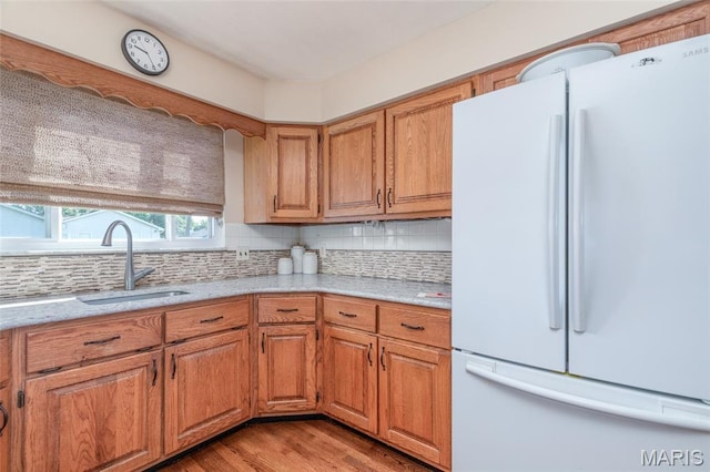 4319 Sinnwell Dr, Saint Louis, MO 63123 - kitchen featuring freestanding refrigerator, backsplash, light wood-style flooring, and brown cabinets