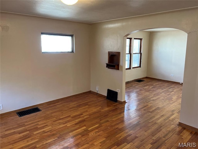 10052 Valley Dr, Riverview, MO 63137 - spare room featuring arched walkways, plenty of natural light, wood finished floors, and baseboards