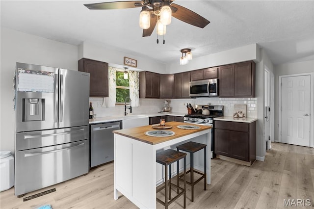1998 Ridgeway Dr, Arnold, MO 63010 - kitchen with stainless steel appliances, dark brown cabinets, tasteful backsplash, and light wood-type flooring