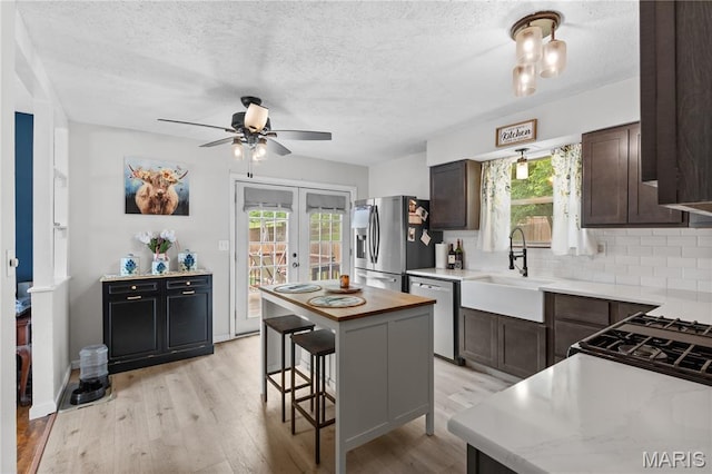 1998 Ridgeway Dr, Arnold, MO 63010 - kitchen with dishwashing machine, stainless steel refrigerator with ice dispenser, a sink, dark brown cabinets, and a textured ceiling