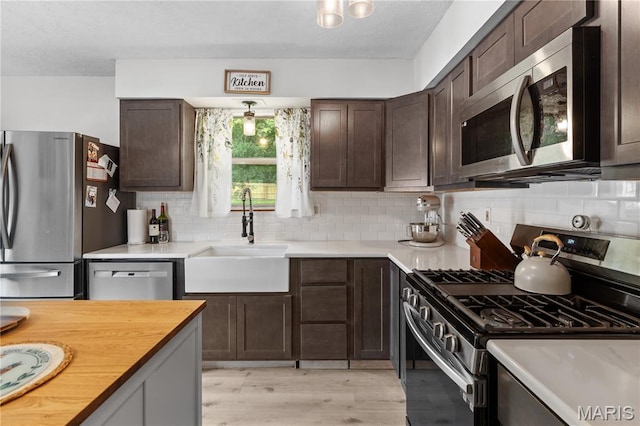 1998 Ridgeway Dr, Arnold, MO 63010 - kitchen with appliances with stainless steel finishes, a sink, dark brown cabinets, backsplash, and light wood-type flooring