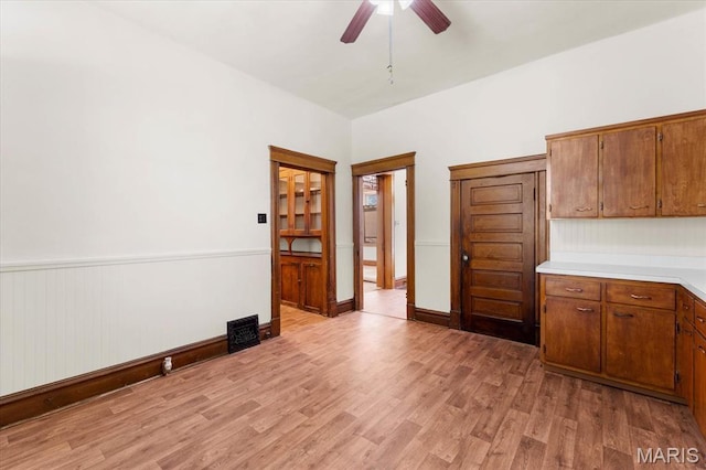 207 Voss Pl, Belleville, IL 62220 - kitchen featuring light countertops, light wood-style flooring, brown cabinetry, a ceiling fan, and a wainscoted wall