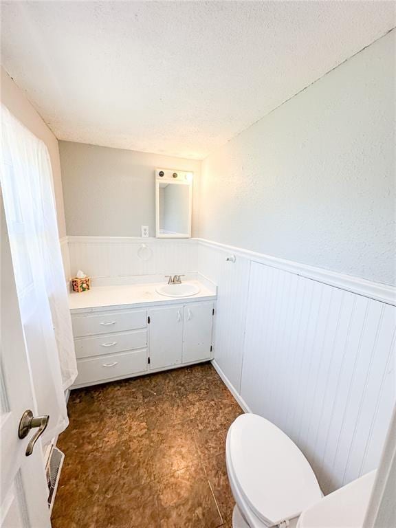 1110 W 3rd St, Salem, MO 65560 - bathroom featuring a wainscoted wall, toilet, vanity, and a textured ceiling
