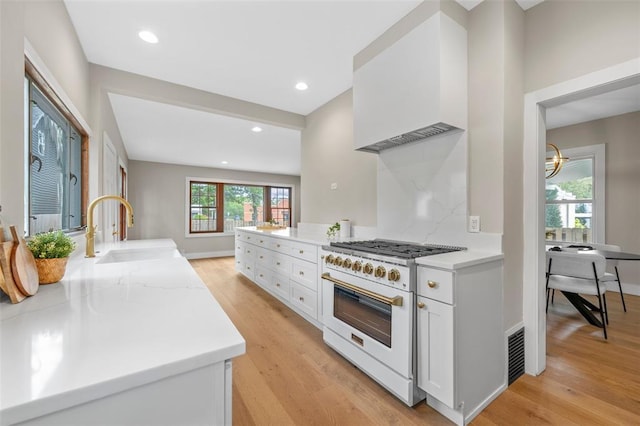 514 S Gore Ave, Saint Louis, MO 63119 - kitchen with high end stove, a sink, light wood-type flooring, white cabinetry, and recessed lighting