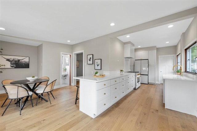 514 S Gore Ave, Saint Louis, MO 63119 - kitchen featuring white appliances, light countertops, a breakfast bar, light wood-style flooring, and white cabinets