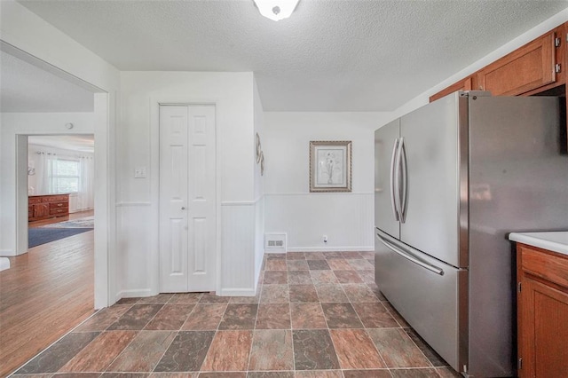 1707 S Mcarthur Ave, Salem, MO 65560 - kitchen with freestanding refrigerator, brown cabinets, a textured ceiling, baseboards, and light countertops