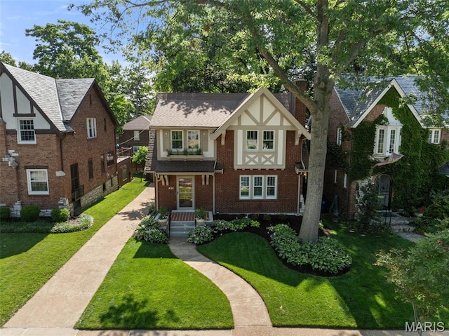 436 W Point Ct, Saint Louis, MO 63130 - tudor house featuring a front lawn, brick siding, and a chimney