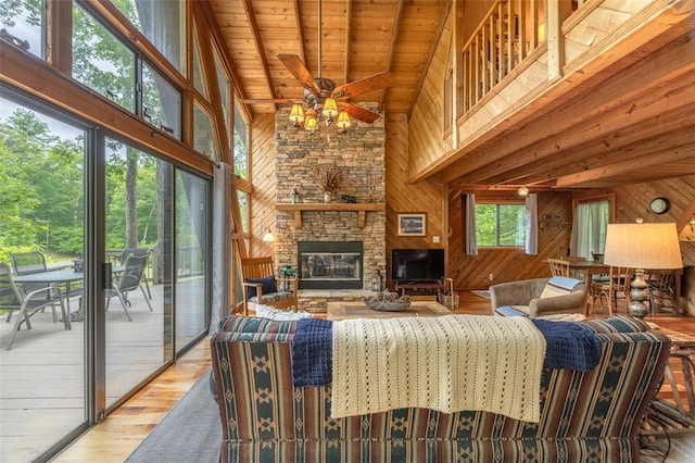 2441 Alpine Lake Dr, Innsbrook, MO 63390 - living room with high vaulted ceiling, wood walls, light wood-style flooring, a ceiling fan, and a fireplace