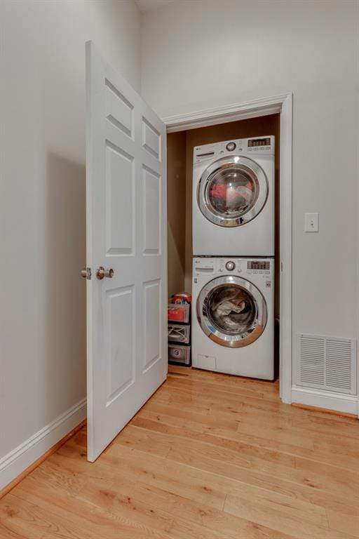 2628 Indiana Ave, Saint Louis, MO 63118 - laundry room with stacked washer / dryer, light wood-style floors, and baseboards