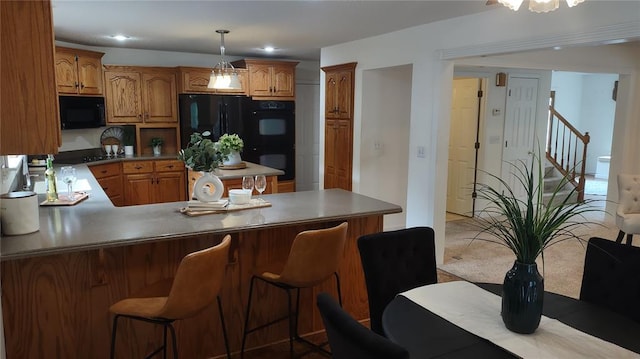 1059 Wolf Crk, Staunton, IL 62088 - kitchen featuring black appliances, brown cabinetry, a peninsula, decorative light fixtures, and a kitchen bar
