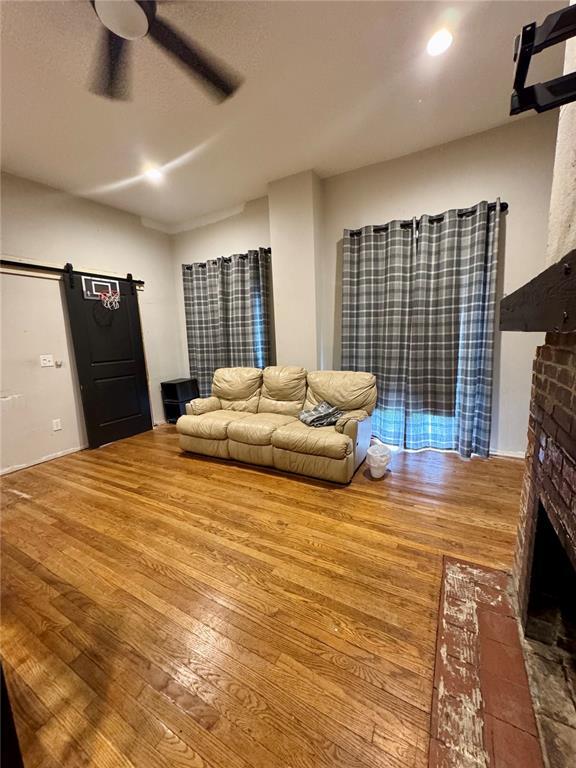 10321 Old 79, Hannibal, MO 63401 - living area with a barn door, a fireplace, hardwood / wood-style floors, and a ceiling fan