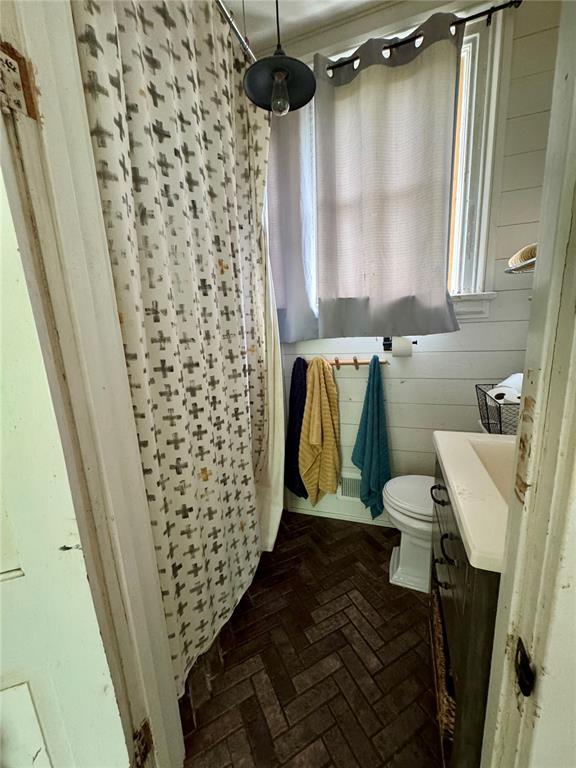 10321 Old 79, Hannibal, MO 63401 - bathroom with vanity, brick floors, a shower with curtain, toilet, and wood walls