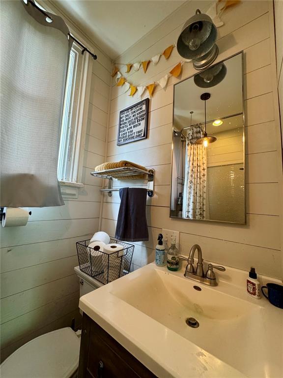 10321 Old 79, Hannibal, MO 63401 - bathroom featuring vanity, toilet, a shower with shower curtain, and wooden walls