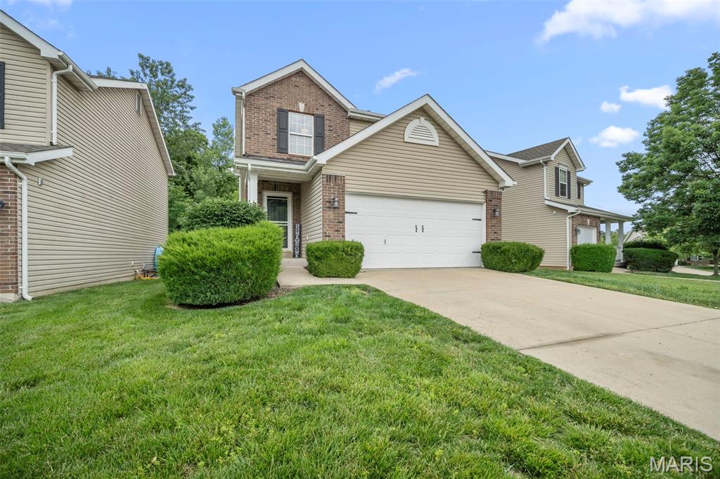 159 Brushy Brook Dr, Ofallon, MO 63366 - traditional-style home with brick siding, driveway, a garage, and a front yard