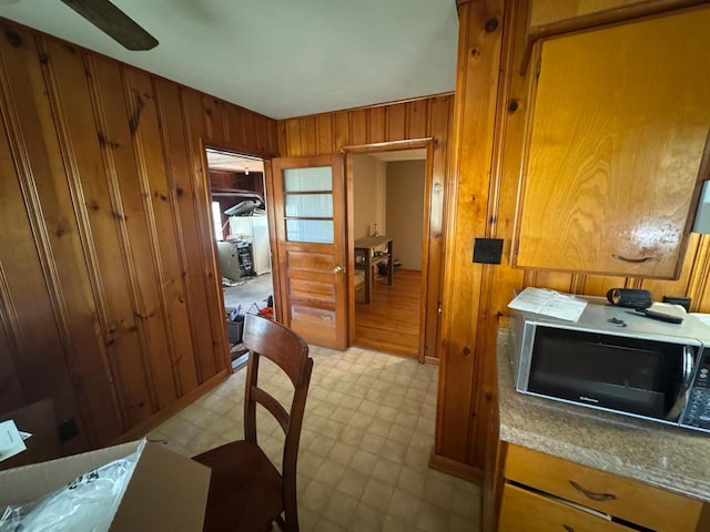 511 N 5th St, La Grange, MO 63448 - kitchen featuring light flooring, wooden walls, brown cabinets, and ceiling fan