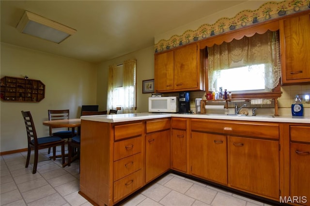 411 S Walnut St, Mount Olive, IL 62069 - kitchen with a sink, white microwave, light countertops, brown cabinets, and a peninsula