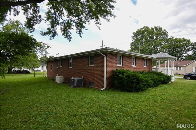 411 S Walnut St, Mount Olive, IL 62069 - view of side of property featuring central AC, a lawn, and brick siding