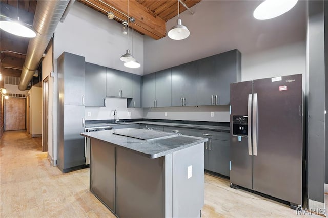 1312 Washington Ave Unit 2A, Saint Louis, MO 63103 - kitchen with stainless steel refrigerator with ice dispenser, black electric cooktop, a kitchen island, decorative light fixtures, and freestanding refrigerator