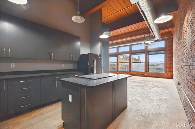 1312 Washington Ave Unit 2A, Saint Louis, MO 63103 - kitchen with stainless steel fridge, brick wall, light wood-style floors, a kitchen island, and electric stovetop