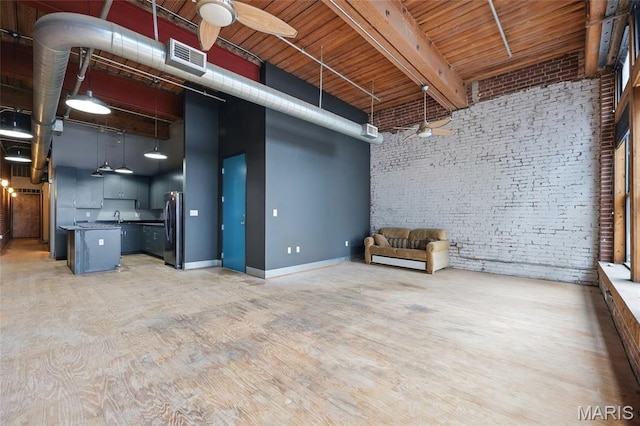 1312 Washington Ave Unit 2A, Saint Louis, MO 63103 - unfurnished living room featuring brick wall, ceiling fan, a high ceiling, beamed ceiling, and light wood-style flooring