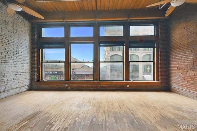 1312 Washington Ave Unit 2A, Saint Louis, MO 63103 - empty room featuring ceiling fan, brick wall, wood finished floors, a wood ceiling with exposed beams, and a high ceiling