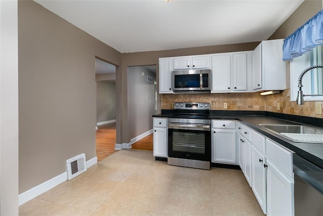 2447 Hartland Ave, Sycamore Hills, MO 63114 - kitchen with appliances with stainless steel finishes, dark countertops, baseboards, backsplash, and white cabinetry