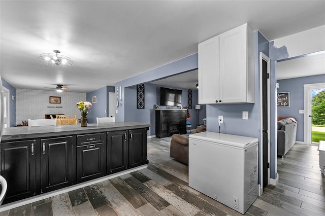 11454 State Highway 72, Millersville, MO 63766 - kitchen with a fireplace, dark cabinetry, fridge, open floor plan, and white cabinets