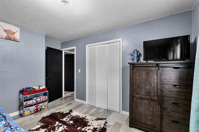 11454 State Highway 72, Millersville, MO 63766 - bedroom featuring a textured ceiling, light wood-type flooring, a textured wall, a closet, and baseboards