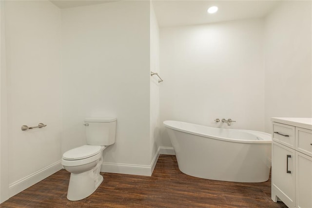 702 E Warren St, Bunker Hill, IL 62014 - bathroom featuring a freestanding bath, wood finished floors, vanity, toilet, and recessed lighting