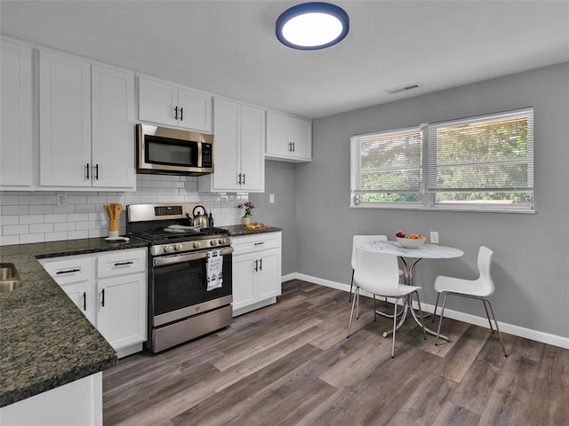 8668 Engler Ave, St John, MO 63114 - kitchen featuring stainless steel appliances, decorative backsplash, dark stone counters, baseboards, and white cabinetry