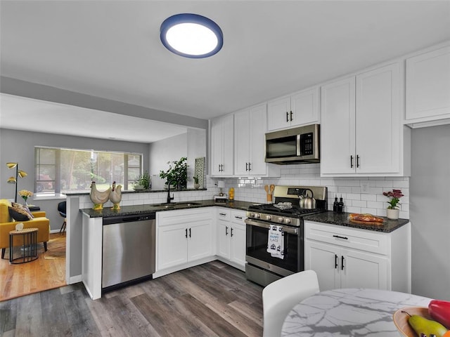 8668 Engler Ave, St John, MO 63114 - kitchen with stainless steel appliances, a sink, dark stone countertops, and backsplash