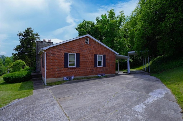 524 W 8th St, Hermann, MO 65041 - view of side of home featuring brick siding, driveway, a chimney, a lawn, and a carport