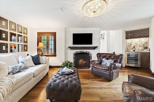 32 Woodoaks Trl, Ladue, MO 63124 - living room with wine cooler, bar area, a fireplace with flush hearth, wood finished floors, and a chandelier