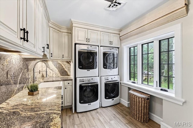 32 Woodoaks Trl, Ladue, MO 63124 - laundry room with estacked washer and dryer, washer and clothes dryer, cabinet space, and light wood finished floors
