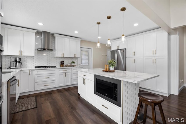 4163 Attleboro Ct, Saint Charles, MO 63304 - kitchen with wall chimney range hood, appliances with stainless steel finishes, white cabinetry, backsplash, and dark wood-style flooring