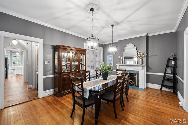 232 N Newstead Ave, Saint Louis, MO 63108 - dining area with wood-type flooring, baseboards, a chandelier, a fireplace with flush hearth, and crown molding