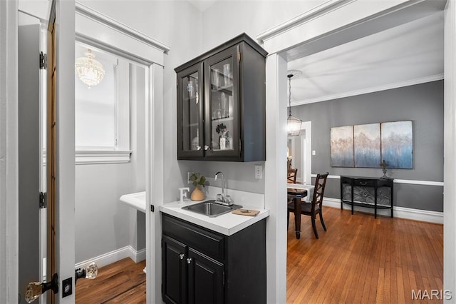 232 N Newstead Ave, Saint Louis, MO 63108 - kitchen featuring a sink, dark cabinets, light countertops, glass insert cabinets, and wood finished floors