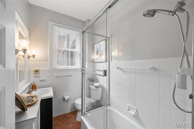 232 N Newstead Ave, Saint Louis, MO 63108 - bathroom with vanity, toilet, tile patterned floors, tile walls, and combined bath / shower with glass door