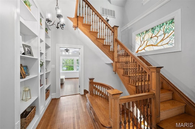 232 N Newstead Ave, Saint Louis, MO 63108 - stairs with hardwood / wood-style floors, a chandelier, ceiling fan, built in shelves, and a towering ceiling