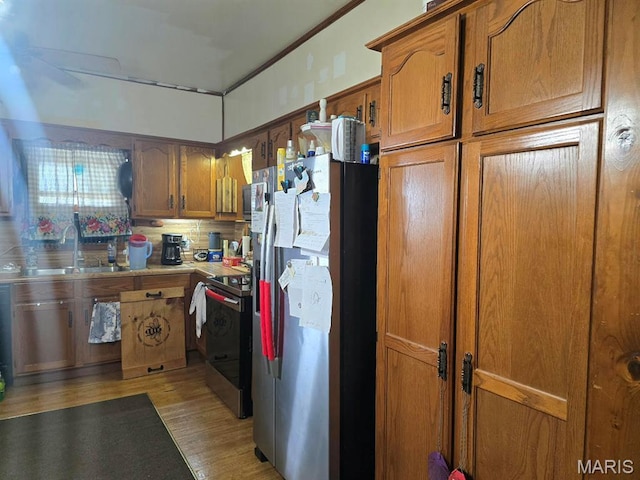 346 S Locust St, Dexter, MO 63841 - kitchen featuring stainless steel appliances, a sink, light wood-style flooring, brown cabinetry, and backsplash