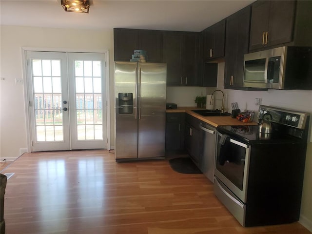 1 Wild Deer Ln, Saint Peters, MO 63376 - kitchen with appliances with stainless steel finishes, a sink, french doors, light wood-style floors, and dark cabinetry