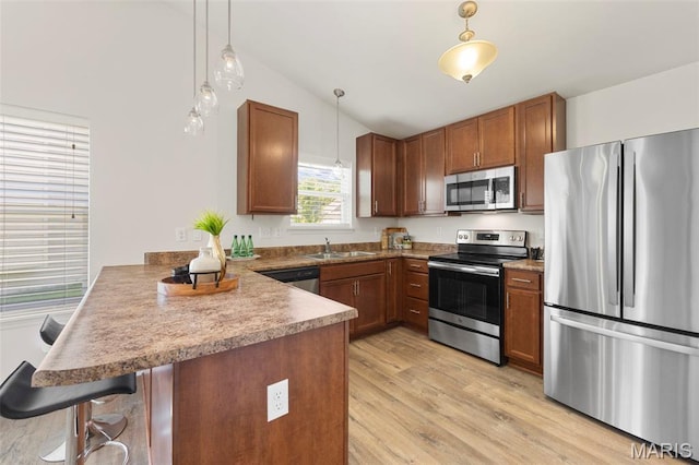 119 Hidden Bluffs Dr, Lake St Louis, MO 63367 - kitchen with appliances with stainless steel finishes, a peninsula, lofted ceiling, decorative light fixtures, and light wood-type flooring