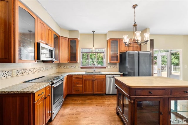 1519 Scofield Valley Ln, Wildwood, MO 63038 - kitchen featuring stainless steel appliances, a chandelier, decorative backsplash, and light wood-type flooring