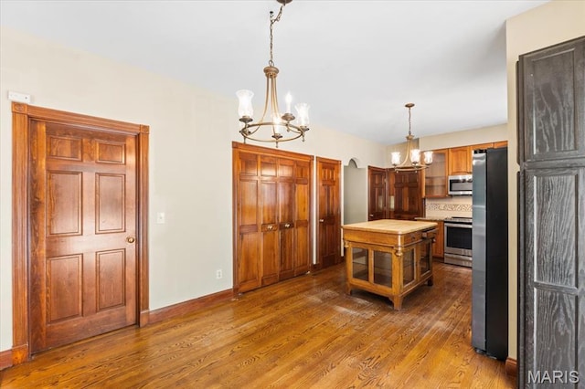 1519 Scofield Valley Ln, Wildwood, MO 63038 - kitchen featuring a chandelier, appliances with stainless steel finishes, dark wood finished floors, hanging light fixtures, and glass insert cabinets