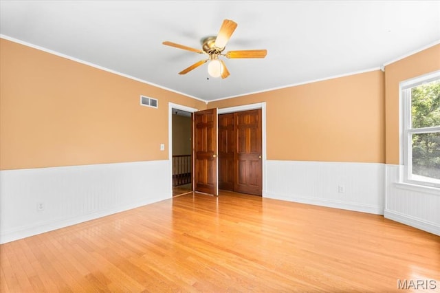 1519 Scofield Valley Ln, Wildwood, MO 63038 - empty room with wood finished floors, a wainscoted wall, a ceiling fan, and crown molding