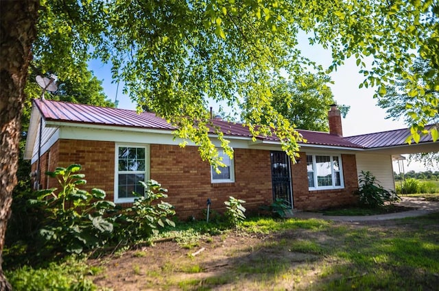 216 Patty Lynn Dr, Kennett, MO 63857 - view of front facade featuring a chimney, brick siding, and metal roof
